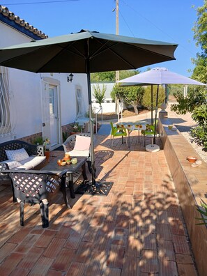 Un patio con mobiliario exterior, una zona de estar cubierta y vistas a un cuerpo de agua.