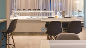 A modern dining area with a central counter, chairs, and a decorative window with vertical blinds. - Albatros Hotel (Corfu)
