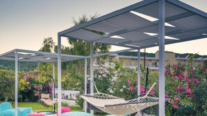 A covered outdoor seating area with a hammock, cushions, and a pergola structure. - Albatros Hotel (Corfu)