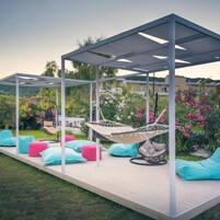 A covered outdoor seating area with a hammock, cushions, and a pergola structure.