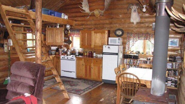 L’intérieur d’un chalet rustique comprenant une cuisine, un coin repas et une cheminée.
