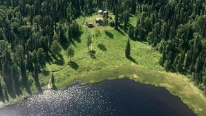 Une vue aérienne d’une zone boisée, avec un petit groupe de bâtiments entourés d’arbres denses.