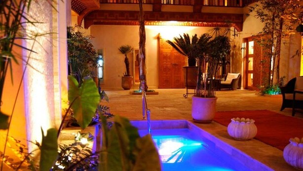 A courtyard with a pool, potted plants, and a wooden door. - Riad Flam (Marrakech)