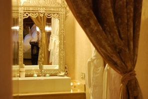 A bathroom with an ornate mirror, a sink, and a towel rack.