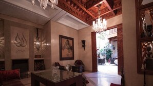 A spacious room with a glass-top table, a fireplace, and a chandelier. - Riad Flam (Marrakech)