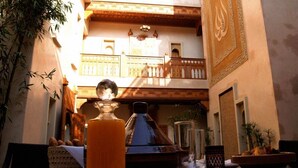 A table set for a meal with a bottle of orange juice, a traditional clay pot, and a basket of bread. - Riad Flam (Marrakech)