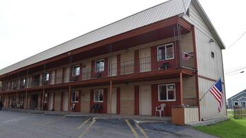 A two-story motel with a red and beige exterior, multiple rooms, and an American flag on the side.