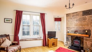 A cozy living room with a fireplace, wooden furniture, and a television. - Grassmarket, Below Edinburgh Castle in Old Town (Edinburgh)