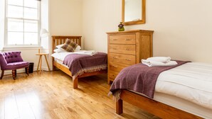 A bedroom with two beds, a wooden dresser, a chair, and a window with curtains. - Grassmarket, Below Edinburgh Castle in Old Town (Edinburgh)