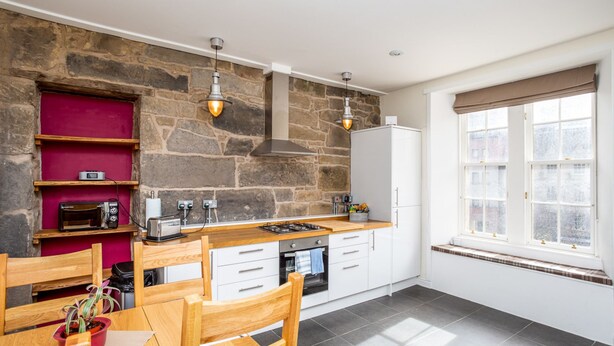 A modern kitchen with stone walls, wooden furniture, and a window with a view. - Grassmarket, Below Edinburgh Castle in Old Town (Edinburgh)