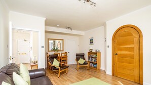 A living room with a sofa, two chairs, a wooden bookshelf, and a large wooden door. - Advocates Close (Edinburgh)
