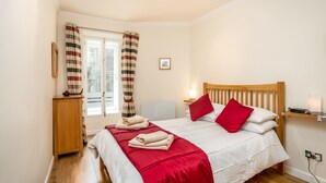A neatly arranged bedroom with a wooden bed, red pillows, and a red blanket. - Advocates Close (Edinburgh)