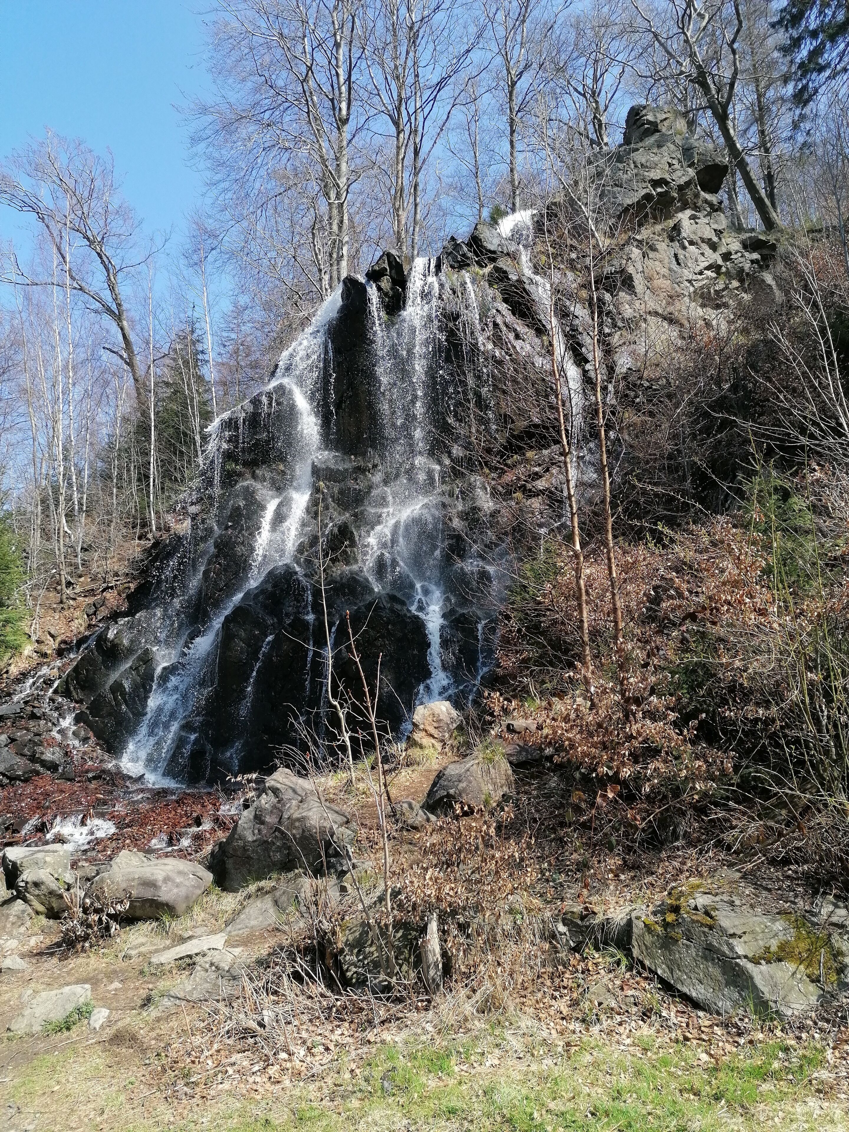A waterfall surrounded by rocky terrain and sparse vegetation.