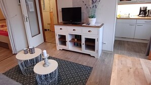 A modern living room with a sofa, two side tables, a TV, and a small kitchen area with a microwave and coffee maker. - Pure resin romance; Time out for 2 persons; feel good and relax (Altenau)