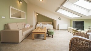 A cozy loft bedroom with a sloped ceiling, a bed, a TV, and a dining area with a table and chairs. - Stylish apartment Luce 3***** by the sea on Krk (Malinska)