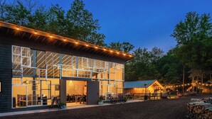 A modern building with large windows and a covered outdoor seating area. - The Fields of Michigan (South Haven)