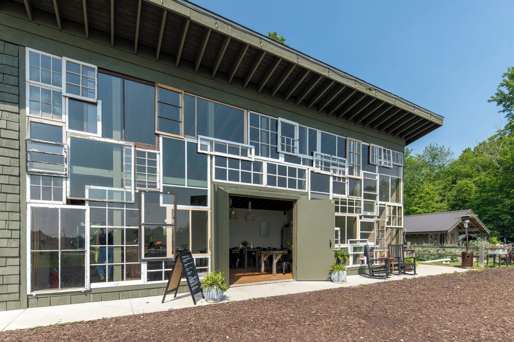 A two-story building with large windows and a covered outdoor seating area.