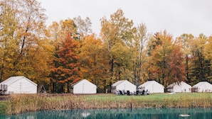 A row of white tents with a lake and autumn trees in the background. - The Fields of Michigan (South Haven)