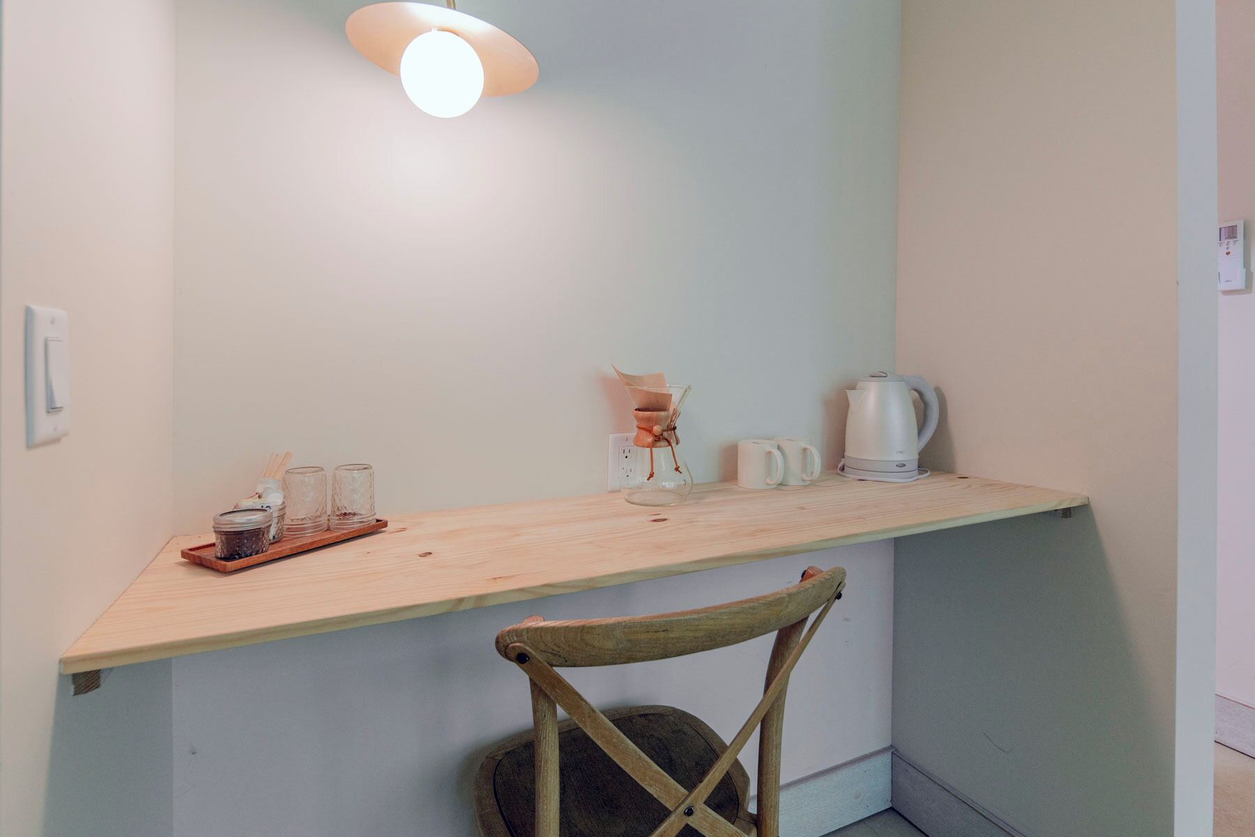 A small, cozy kitchenette with a wooden countertop, a coffee maker, and a glass carafe.