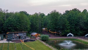 A lakeside lodge with a dining area, outdoor seating, and a pond with a fountain. - The Fields of Michigan (South Haven)