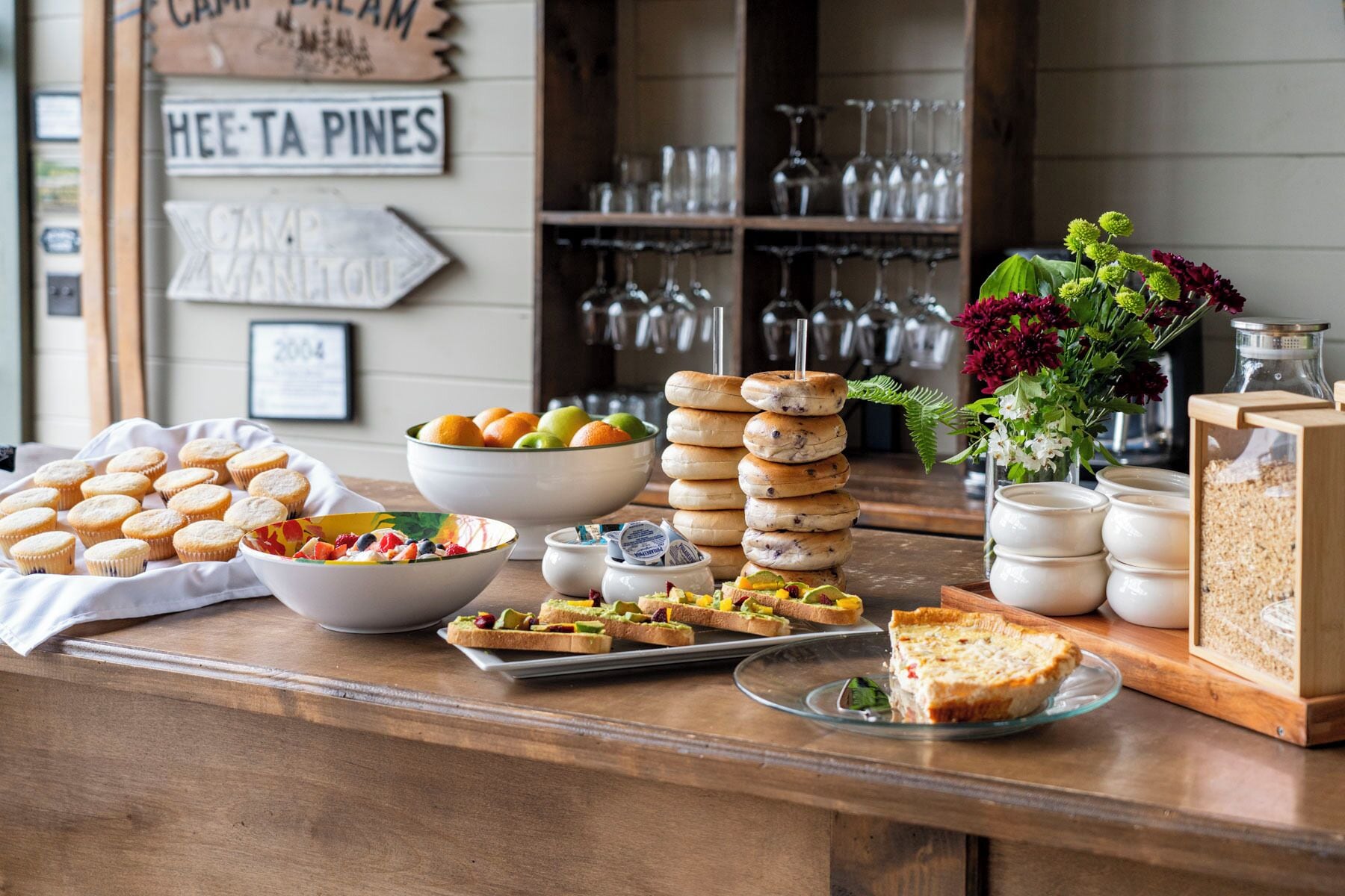 A breakfast buffet with muffins, fruit, bagels, and a pie.