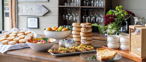A breakfast buffet with muffins, fruit, bagels, and a pie.