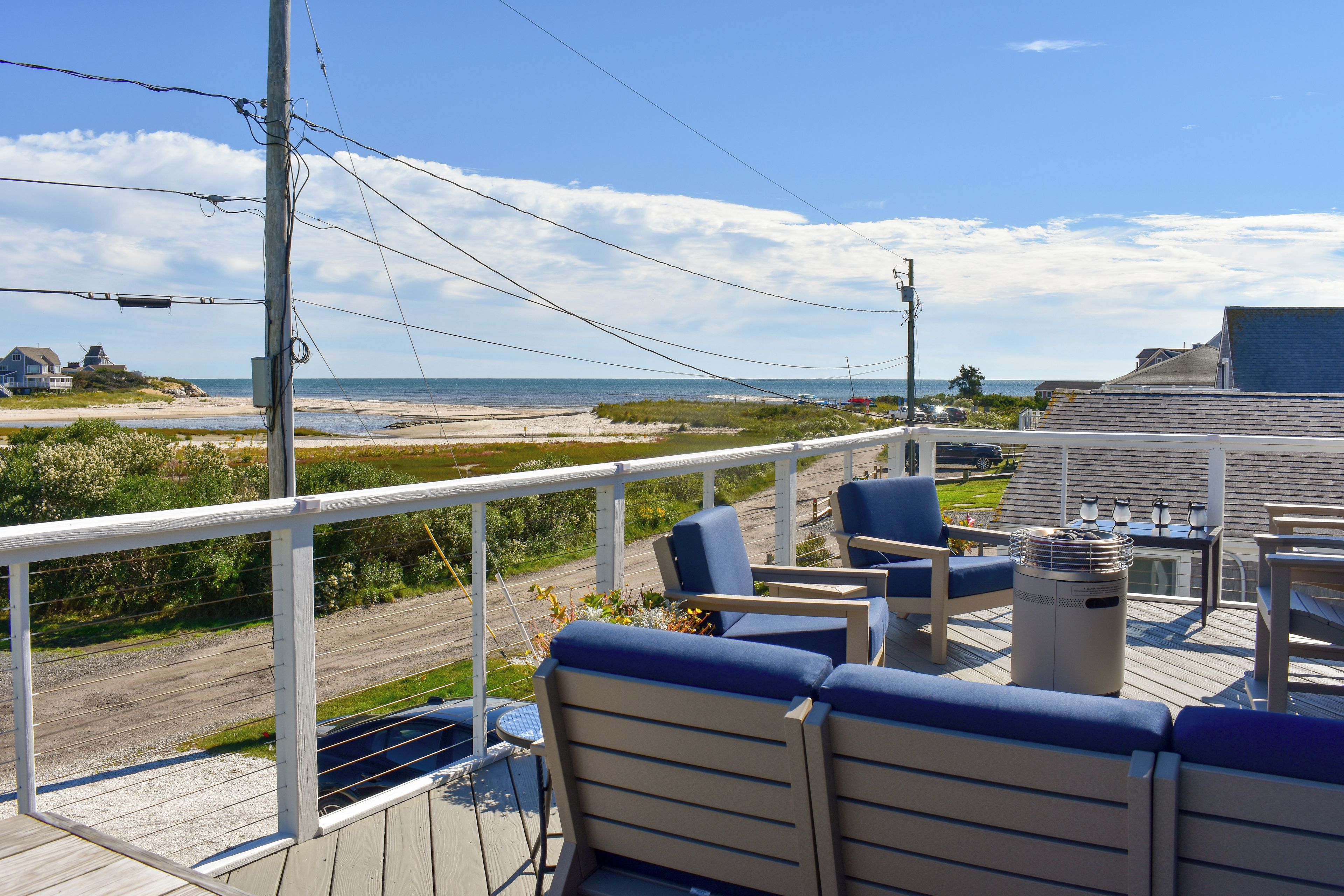 Eine Terrasse mit Sitzgelegenheit, mit Blick auf Strand und Meer.