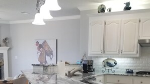 A modern kitchen with a large island, white cabinetry, and a pendant light fixture.
