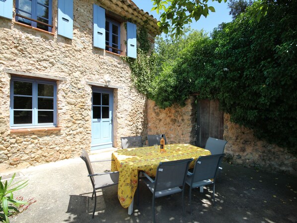 A stone building with a blue door and shutters, a table with a yellow tablecloth, and four chairs. - Lou Penequet, a charming Mas in Provence with shared pool, countryside (Flayosc)