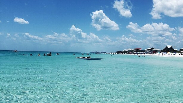 A beach with clear turquoise water, a few people in the distance, and buildings on the shore. - Charming, Chic, Right Next to the Beach (Santa Rosa Beach)
