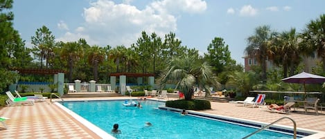A swimming pool with lounge chairs and palm trees.
