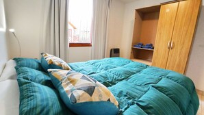 Un dormitorio con cama, armario, ventana y escritorio.