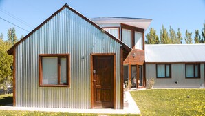 Una casa moderna de dos pisos con fachada de metal y puerta de madera.