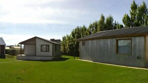Un hilera de tres casas pequeñas de un solo piso, con un jardín césped entre ellas.