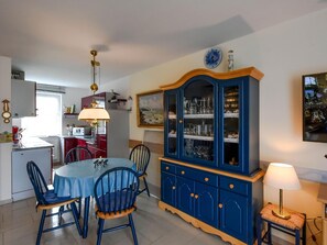 Enjoy meals in this dining area with a round table and four chairs, a cabinet for storage, and a wall-mounted clock.