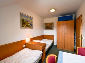 Two single beds with wooden headboards, a bedside table, and a wardrobe with mirror.