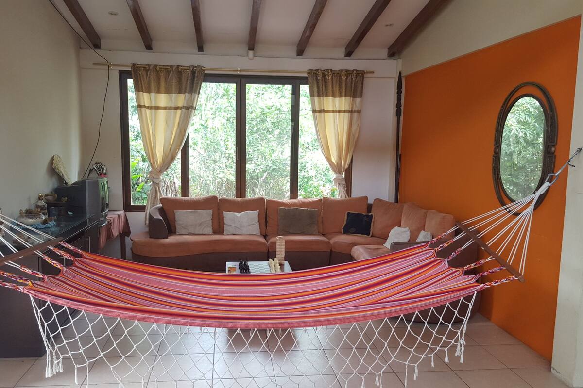 Uma sala de estar com uma rede, um sofá e uma televisão.