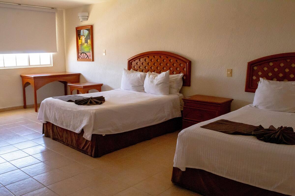 Une chambre d’hôtel avec deux lits, un bureau et une chaise.
