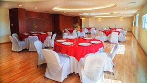 A conference room with round tables, white chairs, and red tablecloths. - Mision Veracruz (Boca del Río)