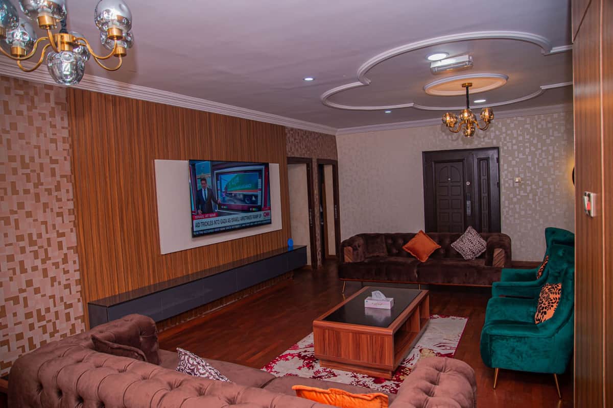 A modern living room with a television, sofas, a coffee table, and a green armchair.