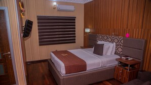 Una camera da letto ben ordinata con un letto grande, comodini, un tavolino da notte e una testiera in legno.