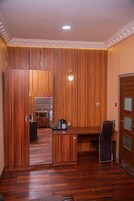 Una habitación con paneles de madera, un escritorio, una silla, una pequeña kitchenette y una puerta con un panel de vidrio.