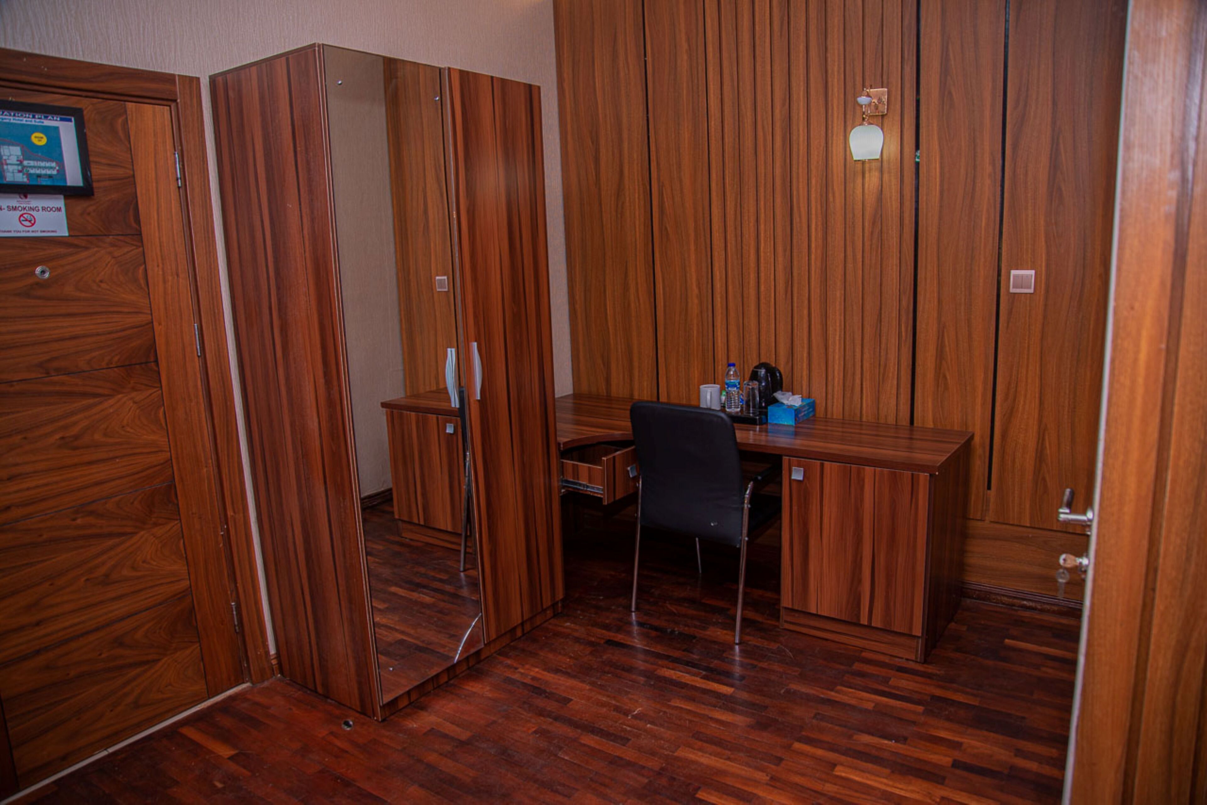 A room with a wooden desk, chair, and wardrobe.