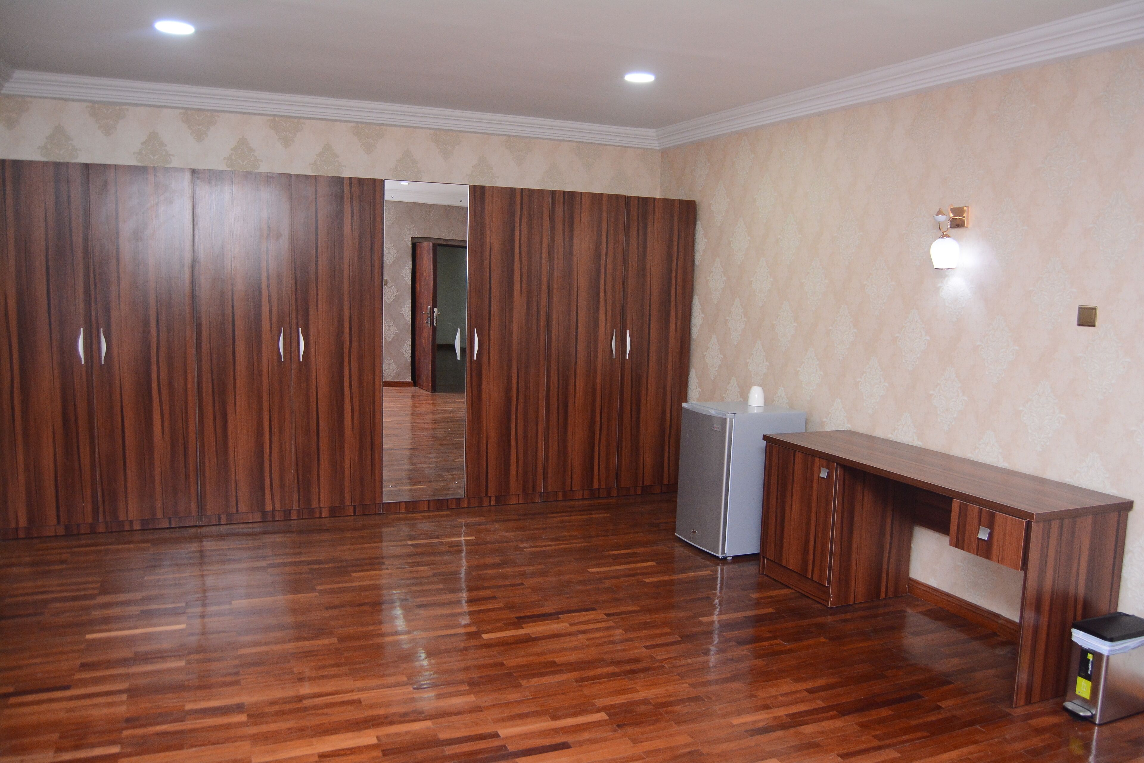 Une pièce avec un plancher en bois, un bureau et une armoire.