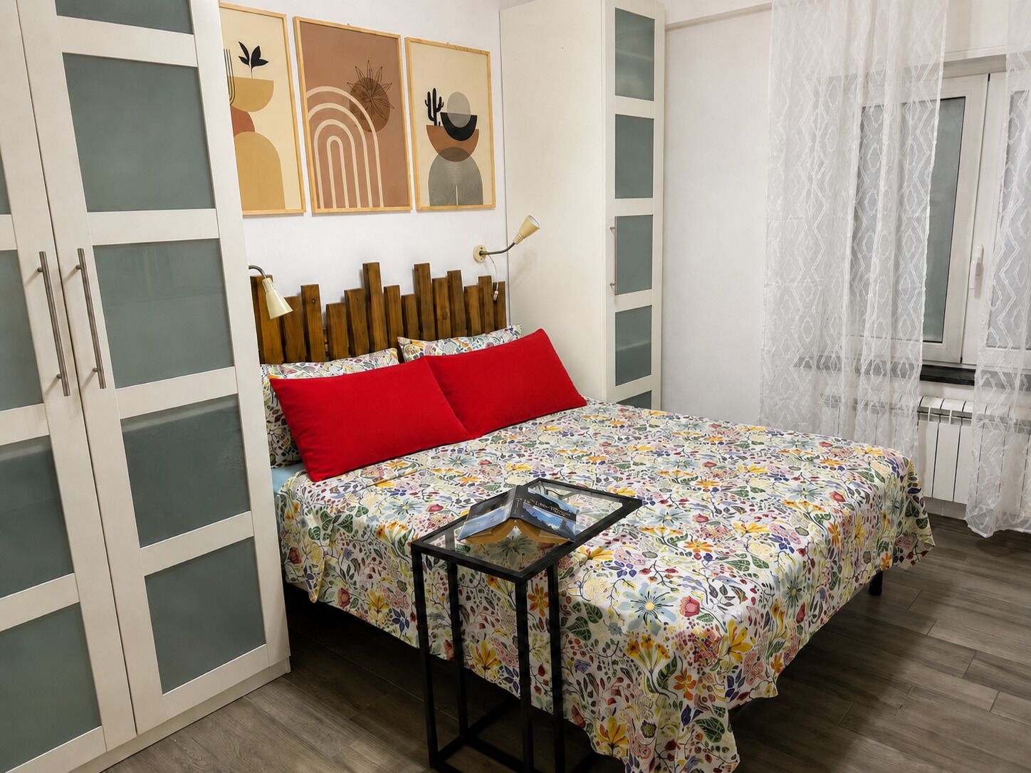Une chambre à coucher avec un lit, une table de chevet, une armoire et une fenêtre avec des rideaux.