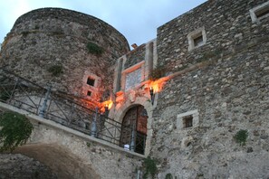 A historical stone building with a round tower, arched doorway, and a plaque.