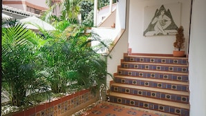 A staircase with colorful tiles leading to a landing with a wall-mounted artwork. - Hostal Paraiso Tayrona (Santa Marta)