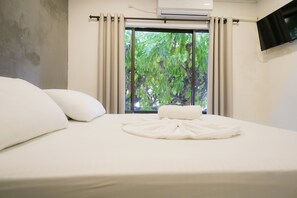 A neatly made bed with white linens and pillows, a window with curtains, and an air conditioning unit above the window. - Paraiso Tayrona Casa de Playa (Santa Marta)
