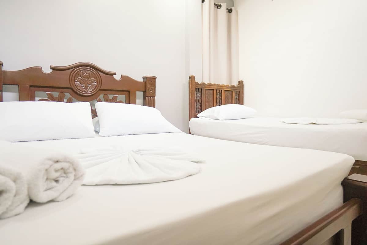 A hotel room with two beds, each with a wooden headboard and white bedding.