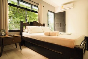 A bedroom with a bed, a nightstand, a window with curtains, and an air conditioning unit. - Paraiso Tayrona Casa de Playa (Santa Marta)